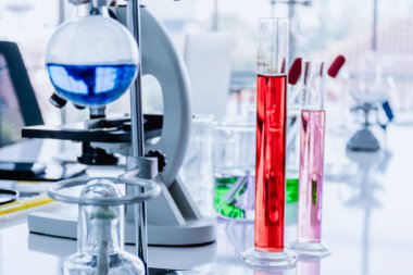 Bulanık kırmızı beher, cam eşyalar, mikroskoplar, test tüpleri, akıllı telefonlar, dizüstü bilgisayarlar ve bilimsel laboratuarlardaki bilimsel ekipmanlar..