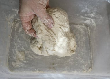 Fırıncının elleri plastik bir kapta hamur yoğuruyor. Ekolojik olarak doğal hamur işleri hazırlar.