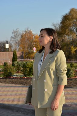 Güz aylarında sokakta açık renk takım elbiseli kahverengi saçlı güzel bir kadının profili..