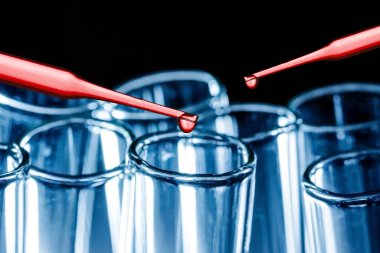 Virüs aşısı araştırma laboratuarı geçmişi. Cam şişelere dökülen kırmızı sıvı pipetler. Kan rengi testi şeffaf sıvı. Boş kopya alanı salgını arka planı. Covid-19 koronavirüs dokuyu yaydı.