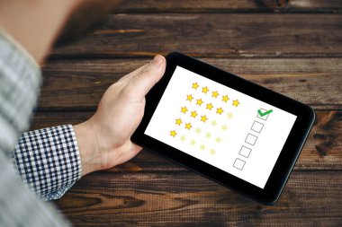 İş adamı elinde internet memnuniyeti anketi olan bir tablet tutuyor. Kaliteli değerlendirme. Bize oran ver. Müşteri derecelendirme geçmişi. 