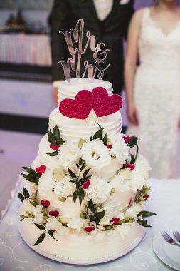 Çiçekler ve kalplerle süslenmiş düğün pastası. 