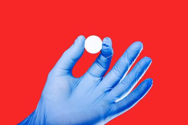 Kırmızıya izole edilmiş beyaz hap tutan mavi lateks eldiven. Sağlık hizmeti ağrı kesici tıbbi geçmişi.