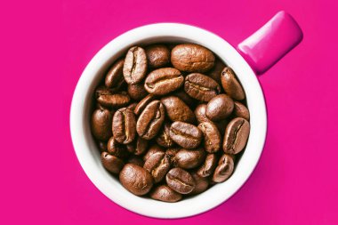 Sabah kahve fincanı soyut desen. Kahve çekirdekleri ile dolu pembe seramik bardak. Boş kopya uzay fasulyesi izole edilmiş arkaplan.