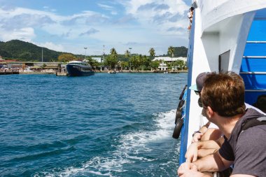 Tayland 'daki güzel güneşli Ko Phi adası. İnsanlar iskeleyi feribottan izliyor. Tropik egzotik tatil manzarası.