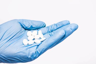Hand in blue latex glove. Virus and bacteria protection. White pills isolated. Doctor holding drugs. Medical clinic empty copy space background. clipart