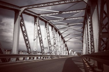 Metal köprü arka planı. Köprü inşaatı. Boş asfalt yol. Fırtınalı hava köprüsü nehrin üzerinde. Polonya 'daki Tykocin köyü.