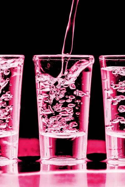 Arka arkaya votka shot. Neon pembe bar karşılaşması. Aydınlatılmış şeffaf cam. Likör döküyorum. Hafta sonu parti alkol geçmişi.