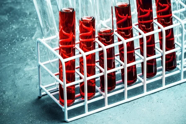 Red fluid in glass flask. Blood color test transparent liquid. Chemistry and science background. Virus vaccine research backdrop.