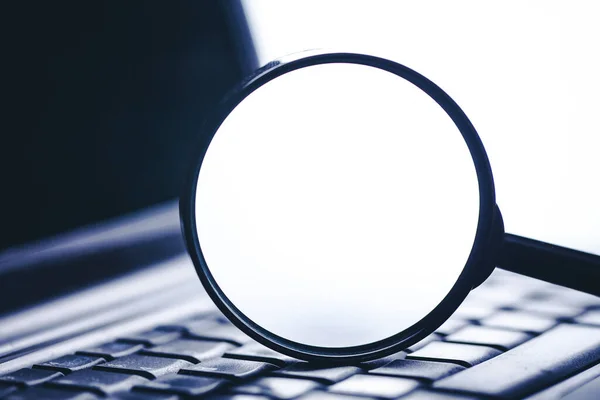 Arama sembolü arka planı. Boş beyaz kopya alanı olan büyüteç. Sığ alan derinliğine sahip bilgisayar klavyesi. Netbook internet taraması. Bilgi arayan dizüstü bilgisayar. Modern dünya araştırma teknolojisi.