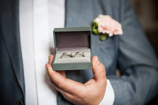 箱の中の金色の結婚指輪 愛のシンボルを保持スーツの新郎 式の背景の準備 ギフトボックスの光沢のあるジュエリー — ストック写真