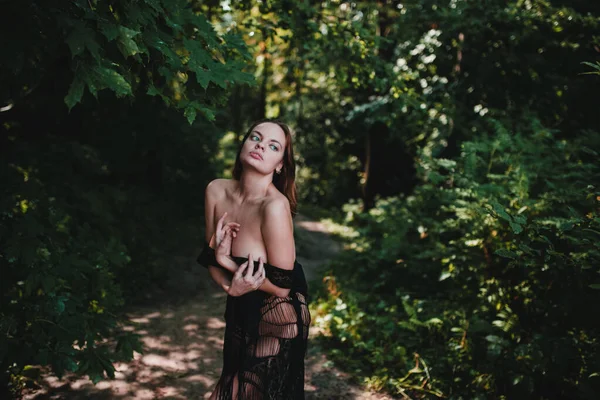 Sarışın, zayıf vücutlu, iri göğüslü, güneşli bir yaz gününde, ormanın sularındaki gezinti alanında poz veren güzel, çıplak bir kız.