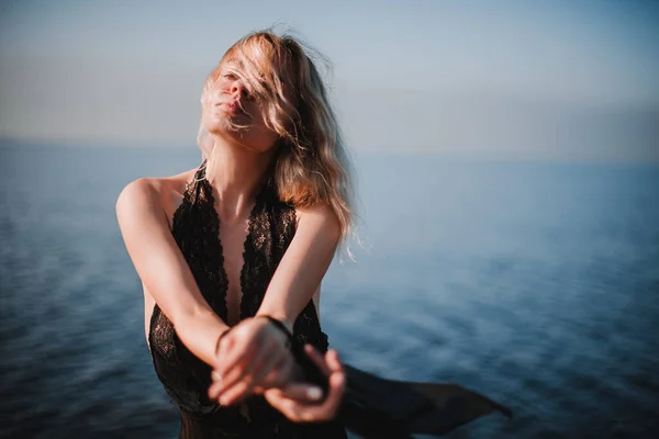 Uzun saçlı çıplak bir kız, zayıf bir vücut ve büyük doğal göğüsler, güneşli bir yaz gününde çıplak bir şekilde ormanda yürüyüş için poz veriyor.