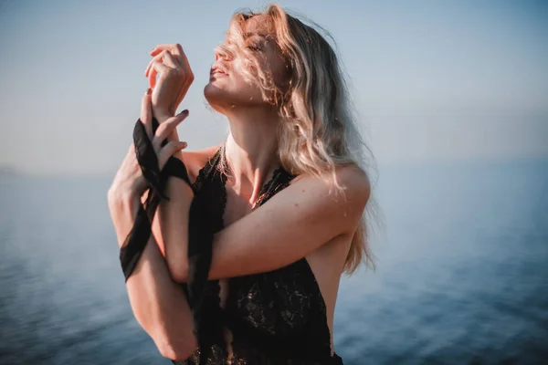 Uzun saçlı çıplak bir kız, zayıf bir vücut ve büyük doğal göğüsler, güneşli bir yaz gününde çıplak bir şekilde ormanda yürüyüş için poz veriyor.