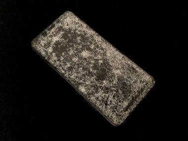 Siyah arka planda kırık camlı cep telefonu..