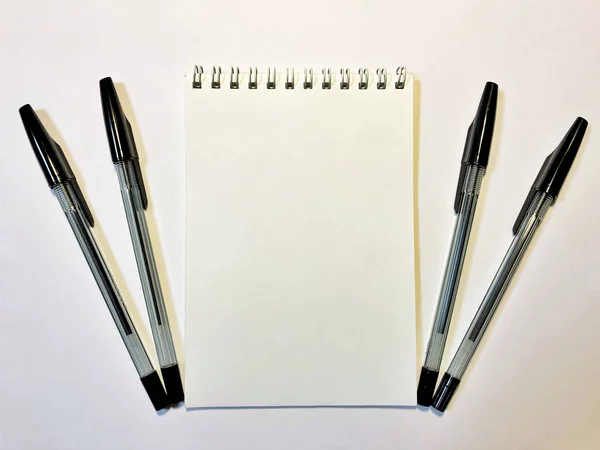 Opened notebook paper with black pen on white desk, copy space — Stockfoto