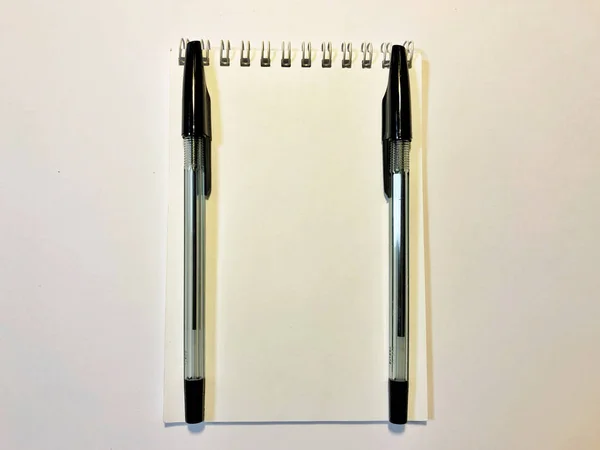 Papel de caderno aberto com caneta preta na mesa branca, espaço de cópia — Fotografia de Stock