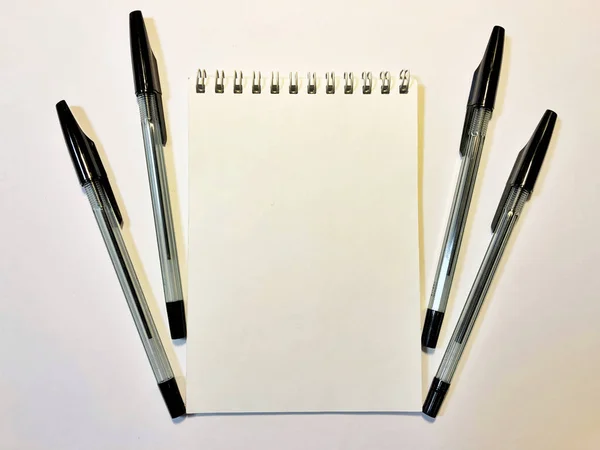 Opened notebook paper with black pen on white desk, copy space — Stockfoto