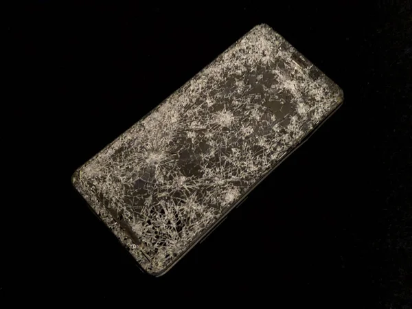 Telefon komórkowy z tłuczonym szkłem na czarnym tle. — Zdjęcie stockowe