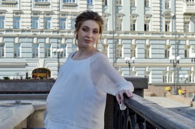 Beyaz bluzlu hamile bir kız. Sarışın kız. Genç kız..