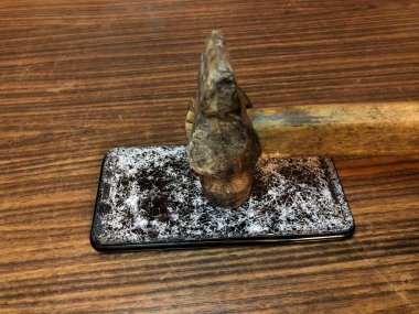 Koyu ahşap arka planda kırık camlı cep telefonu.