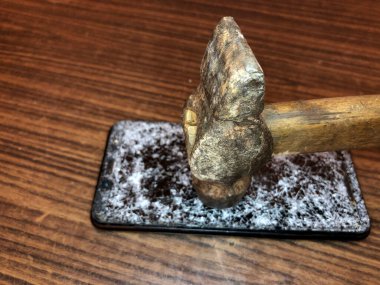 Koyu ahşap arka planda kırık camlı cep telefonu.