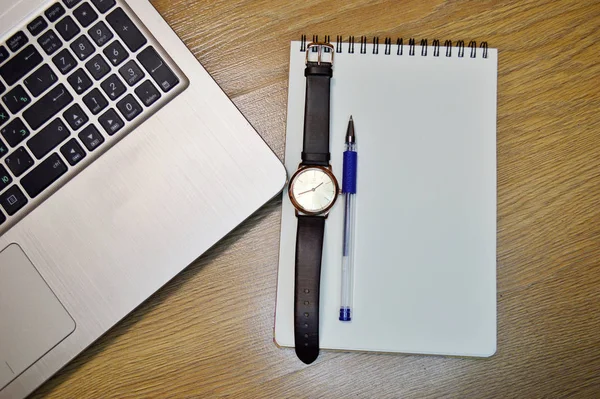 Armbandsur, bärbar dator, penna, anteckningsbok på trä bakgrund — Stockfoto