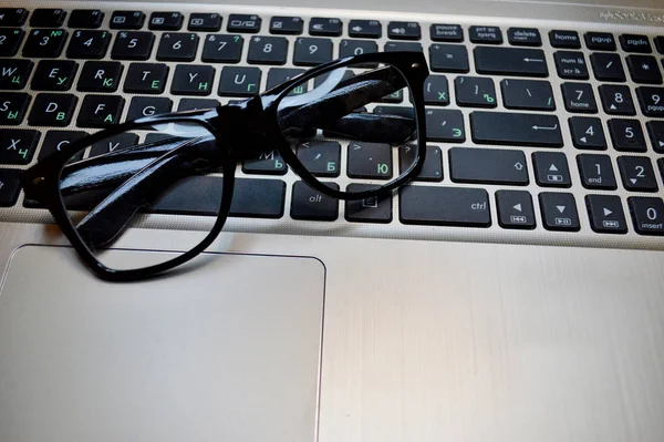 Glasses lie on a black laptop keyboard close-up. — ストック写真