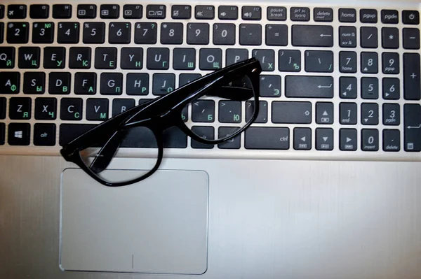 Glasses lie on a black laptop keyboard close-up. — ストック写真