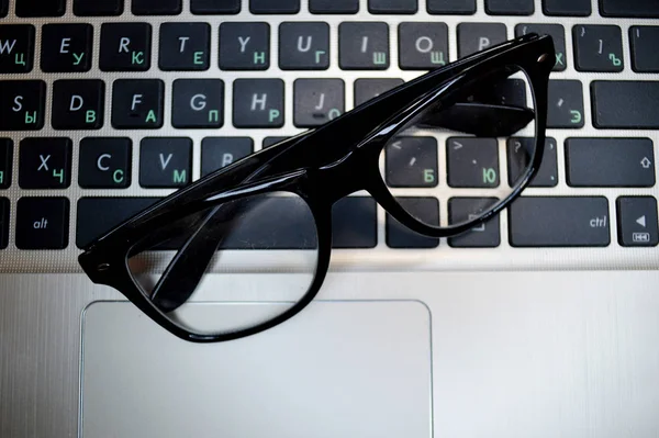 Okulary leżą na czarnym laptopie klawiatury zbliżenie. — Zdjęcie stockowe