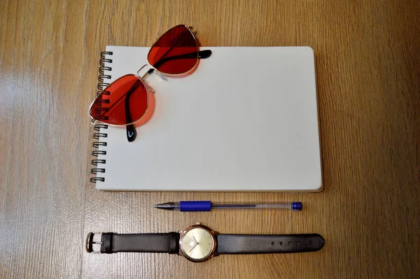 Reloj de muñeca, cuaderno, bolígrafo y gafas sobre fondo de madera —  Fotos de Stock