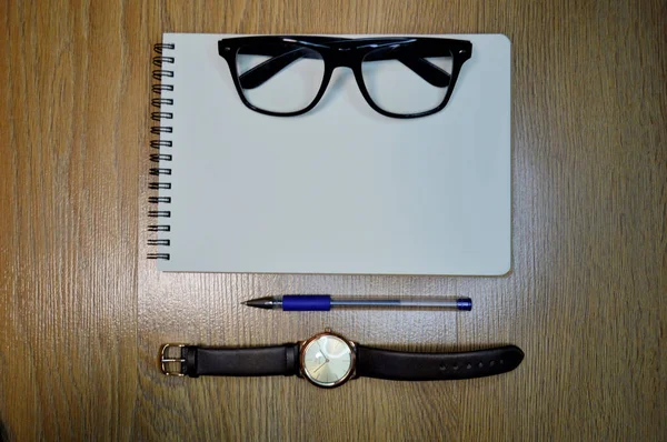 Reloj de muñeca, cuaderno, bolígrafo y gafas sobre fondo de madera —  Fotos de Stock