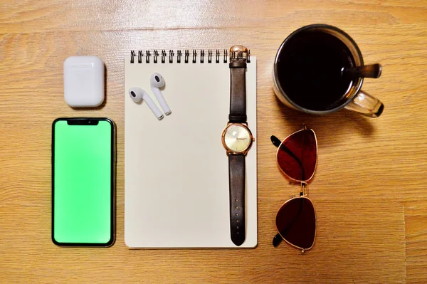 Telefon, Sluchátka, hodinky, notebook, káva, brýle na dřevěném pozadí — Stock fotografie