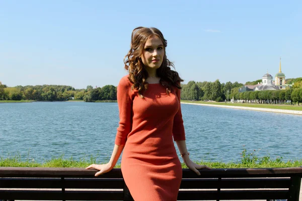 Jeune fille en robe orange se tient près de l'eau . — Photo