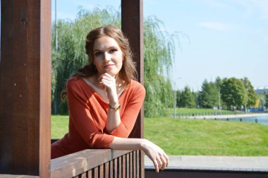 Ahşap bir ağaçlıkta, turuncu elbiseli genç kız..