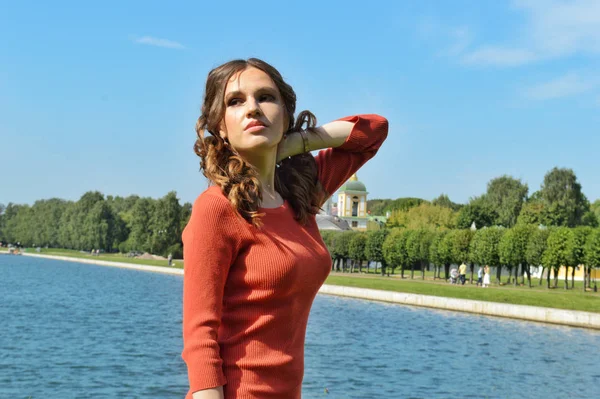 Young girl in orange dress stands near the water. — 스톡 사진