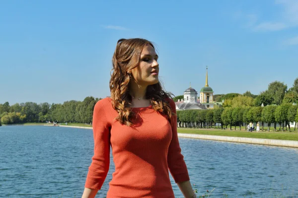 Chica joven en vestido naranja se para cerca del agua . —  Fotos de Stock