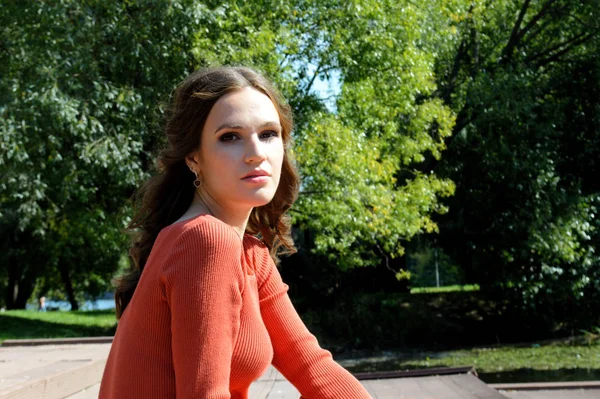 Jeune fille en robe orange s'assoit sur une jetée près de l'eau . — Photo