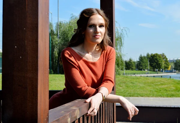 Junges Mädchen in orangefarbenem Kleid in einer Holzlaube. — Stockfoto