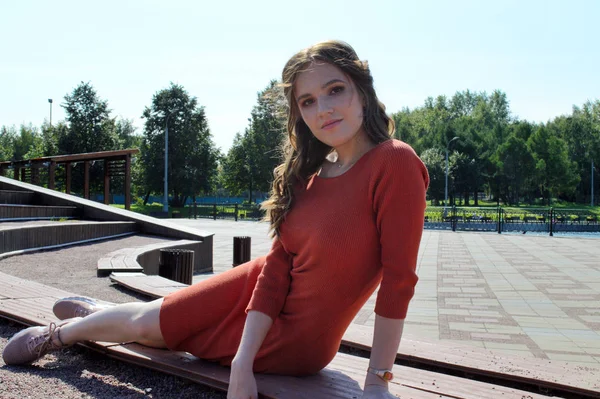 Turuncu elbiseli genç kız ahşap kirişlerin arkasında oturuyor.. — Stok fotoğraf