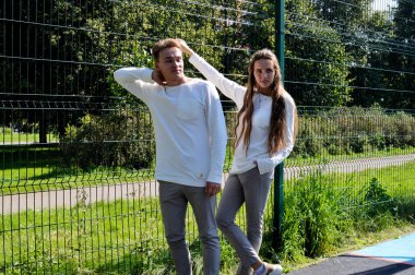 Genç bir kız ve genç bir adam oyun sahasında aynı kıyafetleri giymiş..