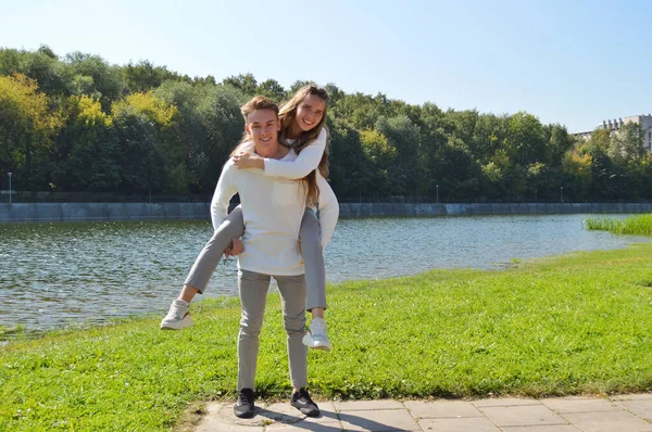 Uma jovem e um jovem com as mesmas roupas mergulham no prado. . — Fotografia de Stock