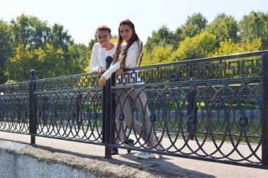 Suya yakın bir köprüde genç bir kız ve aynı kıyafetleri giyen genç bir adam..