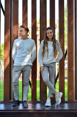 Genç bir kız ve genç bir adam ahşap bir bankta aynı kıyafetleri giymişler..