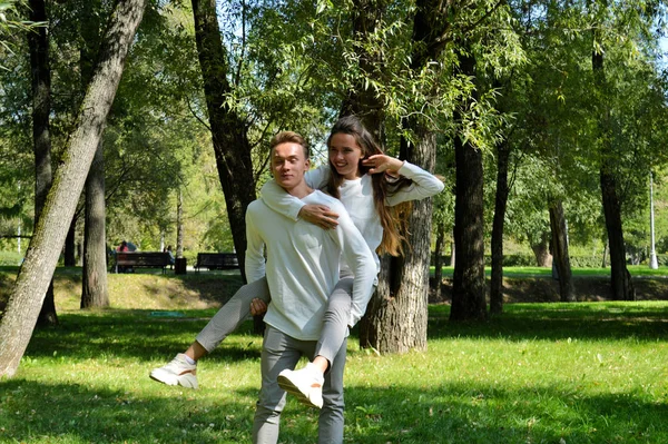 Uma jovem e um jovem com as mesmas roupas mergulham no prado. . — Fotografia de Stock