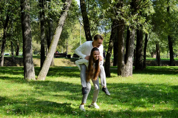 Uma jovem e um jovem com as mesmas roupas mergulham no prado. . — Fotografia de Stock