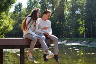 Genç bir kız ve genç bir adam su kenarındaki ahşap iskelede