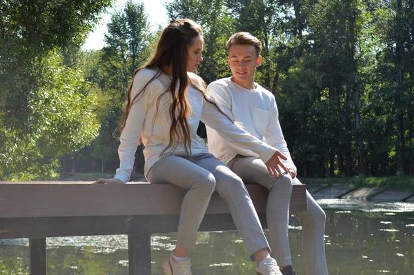 Una joven y un joven en un muelle de madera cerca del agua —  Fotos de Stock