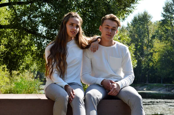 A young girl and a young man on a wooden pier near the water — Stock Photo, Image