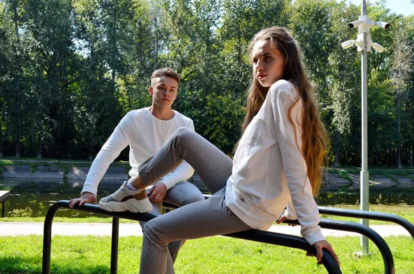 Uma jovem e um jovem com as mesmas roupas no parque infantil . — Fotografia de Stock